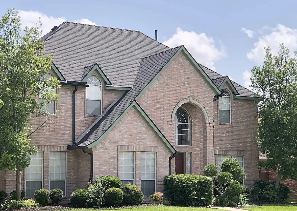 A brick two-story home with a new roof, seen from the street