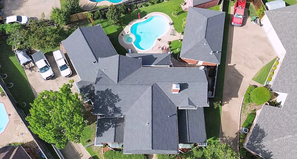 A home with a pool from above, with a new gray shingle roof