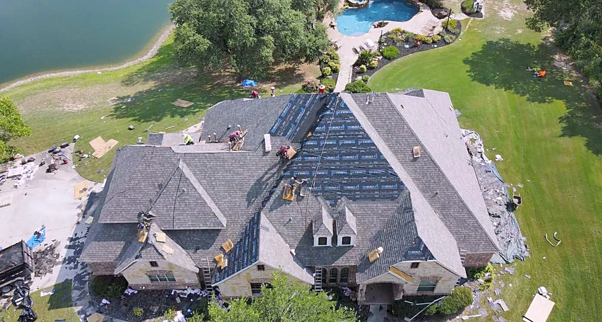 A lakeside home from above with a roof replacement under way