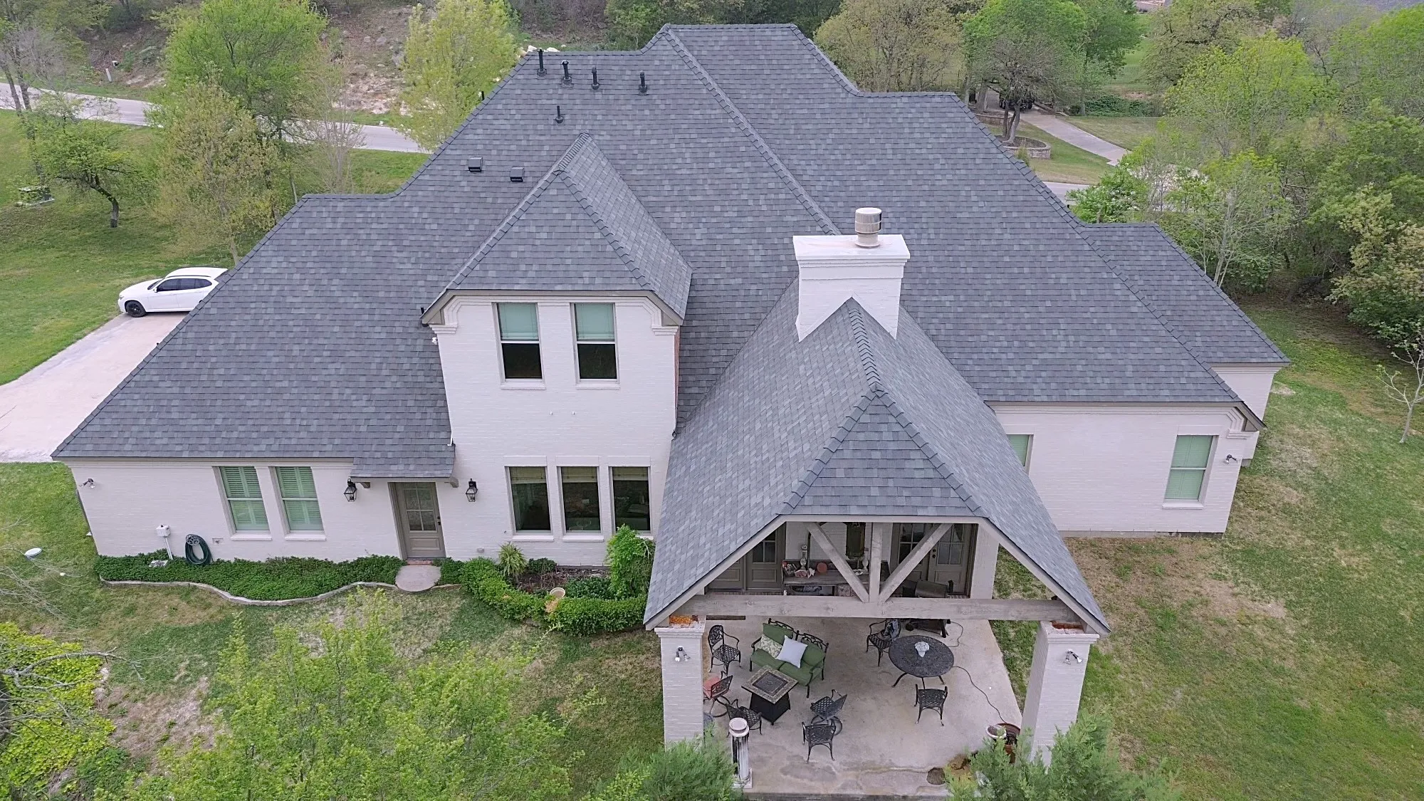 A white brick home from above with a new gray shingle roof