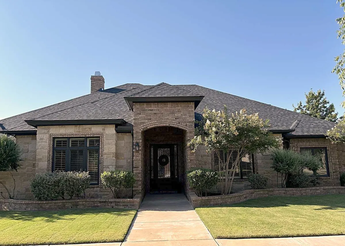 A stone and brick home with a new dark shingle roof